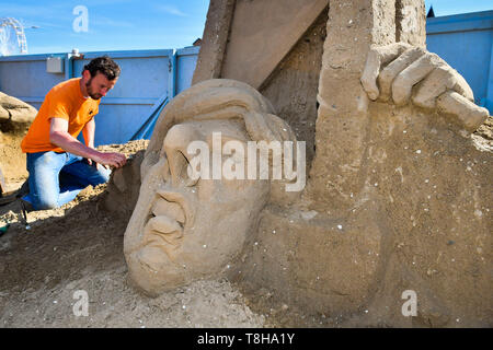 Sand Skulptur Künstler Johannes Hogebrink arbeitet an einem Brexit themed Skulptur an der Weston Sandskulpturenfestival, Weston-super-Mare, mit Premierminister Theresa kann ihren eigenen Kopf abschneiden über eine Guillotine. Stockfoto