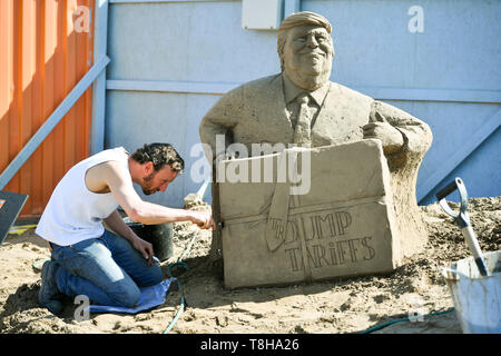 Sand Skulptur Künstler Johannes Hogebrink arbeitet auf den US-Präsidenten Donald Trump auf einem Brexit themed Skulptur an der Weston Sandskulpturenfestival, Weston-super-Mare. Die Skulptur fertig Großbritannien Trennung von Europa auf einem Globus mit Donald Trump Funktion wird im Westen mit seinem Handelsabkommen und Wladimir Putin im Osten lehnte sich auf einem Computer Bildschirm mit gefälschten Nachrichten. Stockfoto