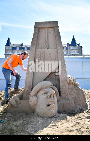 Sand Skulptur Künstler Johannes Hogebrink arbeitet an einem Brexit themed Skulptur an der Weston Sandskulpturenfestival, Weston-super-Mare, mit Premierminister Theresa kann ihren eigenen Kopf abschneiden über eine Guillotine. Stockfoto