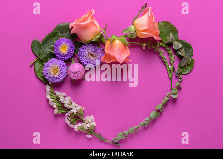 Herz aus Blumen und Blätter auf farbigen Hintergrund Stockfoto