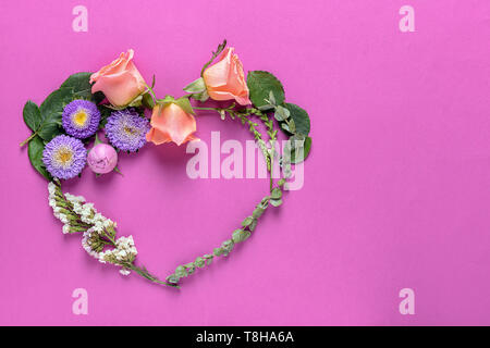 Herz aus Blumen und Blätter auf farbigen Hintergrund Stockfoto