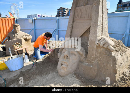 Sand Skulptur Künstler Johannes Hogebrink arbeitet an einem Brexit themed Skulptur an der Weston Sandskulpturenfestival, Weston-super-Mare, mit Premierminister Theresa kann ihren eigenen Kopf abschneiden über eine Guillotine. Stockfoto