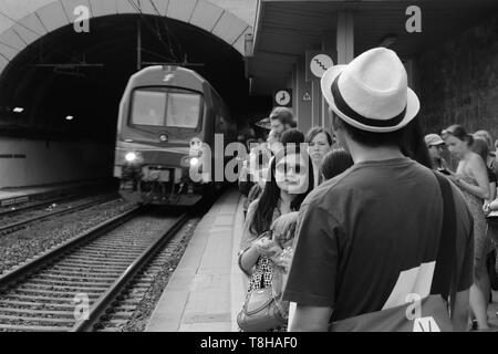 Eine Plattform mit wartenden Fahrgäste als local train Service Ansätze aus dem Tunnel auf Monterosso Bahnhof Ligurien, Italien überfüllt Stockfoto