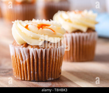 Nahaufnahme einer Karotte Cupcake mit Frischkäse Puderzucker und Cupcakes im Hintergrund Stockfoto