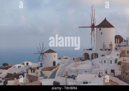 Blick auf die Stadt Oia, Santorini, Griechenland, Detail der Mühlen und der Stadt mit typischen weißen Gebäuden, im Hintergrund das Meer. Stockfoto
