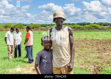 In einem Gebiet von Malawi durch Überschwemmung folgende ein Mann und sein Sohn bepflanzen Mais in seinem Feld Zyklon in der Nähe des Shire Flusses Stockfoto