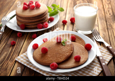 Leckere Pfannkuchen mit Schokolade und Himbeeren auf hölzernen Tischplatte Stockfoto