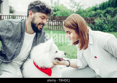 Gesicht Porträt junge Erwachsene lady zärtlich streicheln einen großen weißen Hund. Stockfoto