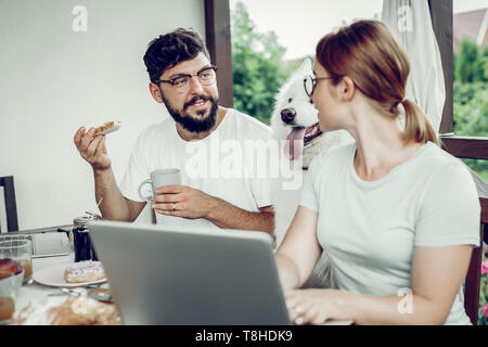 Fröhlicher Mann essen Sandwich und seine Frau Stockfoto