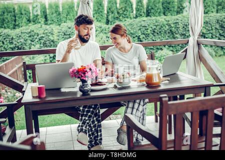 Liebevollen Gatten Frühstücken und Beobachten zeigt auf Laptop im Freien. Stockfoto