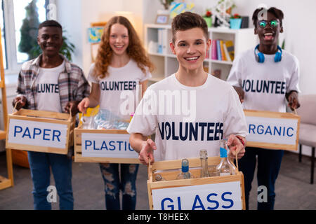 Gut aussehender Teenager Holding Box mit Glasflaschen nach dem Sortieren Stockfoto