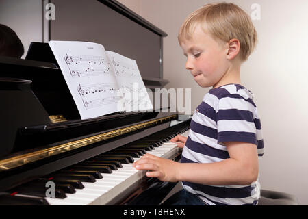 Junge, 4 Jahre, Klavier spielen, mit Konzentration Stockfoto