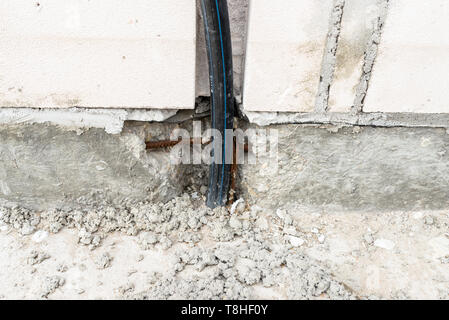 Eine elektrische Hochspannungsleitung ragen aus der Stiftung des Hauses gebaut werden. Stockfoto