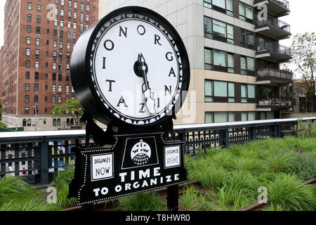 Mai 13, 2019 - New York City, New York, USA - Künstler Ruth Ewan Monumental-Skala Uhr stille Agitator' auf dem Display entlang der Linie auf der West Side in Manhattan. Die Uhr ist eine Abbildung, die ursprünglich für die Industriearbeiter der Welt (IWW) Gewerkschaft der Nordamerikanischen Schriftsteller und Aktivist Ralph Chaplin, die lautet: "Welche Zeit ist es hergestellt? Zeit zu organisieren!" Die Abbildung war einer der vielen Bilder, die auf dem tickerettes", bekannt als 'Silent Rührwerke erschien, "Millionen, die in Rot und Schwarz gedruckt wurden auf gummiertem Papier und von Union Mitglieder tr verteilt Stockfoto