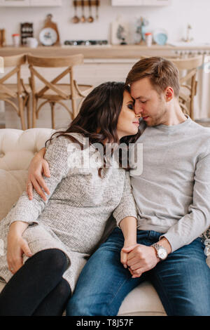 Glückliches Paar sitzt auf der Couch halten sich an den Händen Stockfoto