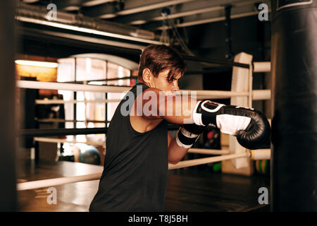 Muskulöse Athleten trainieren Sie im Fitnessraum auf einen Boxsack aus Leder Stockfoto