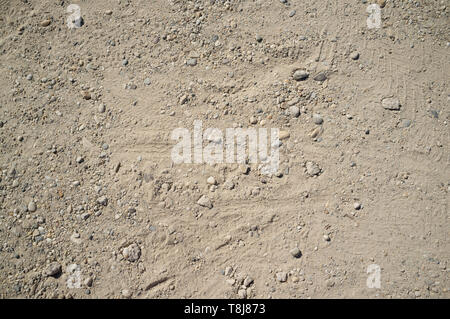 Staubige Straße mit kleinen Felsen, Schmutz, Footprints, Auto- und Fahrradverleih Spuren Textur Stockfoto