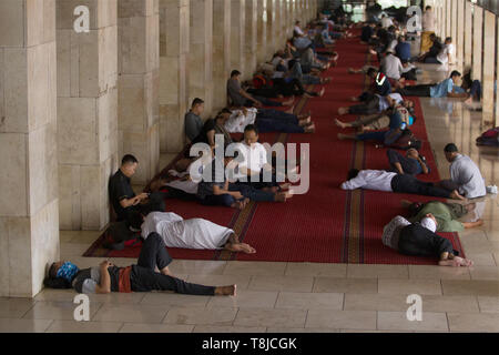 Einige muslimische gesehen während des heiligen Fastenmonats Ramadan an Istiqlal Mosque in Jakarta. Neben dem Lesen der Al-Quran, einige Bewohner beten und Ruhe, während für die Zeit warten Ihr Fasten zu brechen. Stockfoto