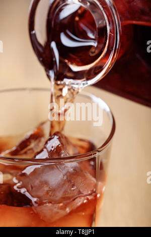 Whiskey wird aus einer Karaffe in ein Glas mit Eis gegossen. Stockfoto