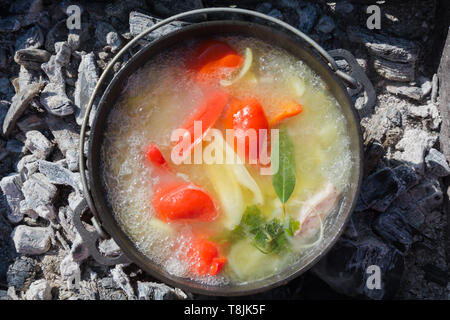 Shurpa Suppe mit Gemüse in großen gusseisernen Kessel outdoor. Sommer essen für Wanderung. Ansicht von oben. Türkische Küche. Stockfoto