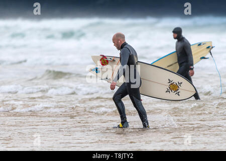 Surfer, die ihre Surfbretter und zu Fuß aus dem Meer auf den Fistral in Newquay in Cornwall. Stockfoto