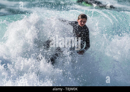 Spektakuläre surfen Aktion als eine junge weibliche Surfer ist in Spray abgedeckt, wie sie reitet eine Welle an Fistral in Newquay in Cornwall.