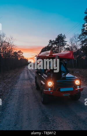 Frau sitzt auf der vorderen Haube auf einem 4x4 Geländewagen. Stockfoto