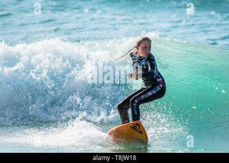 Spektakuläre surfen Aktion als eine junge weibliche Surfer reitet eine Welle an Fistral in Newquay in Cornwall. Stockfoto