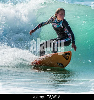 Surfen Aktion als junge Teenager weibliche Surfer reitet eine Welle an Fistral in Newquay in Cornwall. Stockfoto