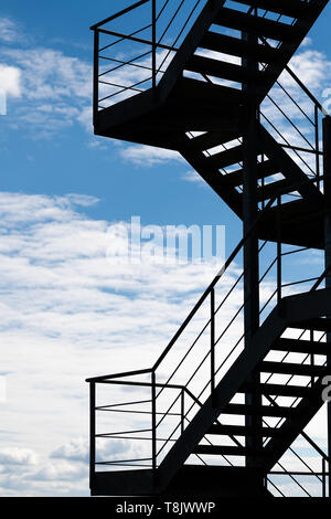 Treppe in den Himmel - ein Feuer entkommen oder eine externe Treppe auf ein Gebäude gegen einen hellen Himmel Silhouette Stockfoto