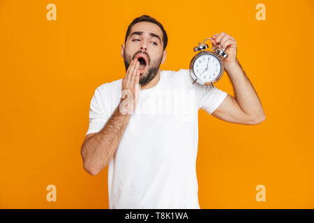 Foto der betroffenen Menschen 30 s in Freizeitkleidung holding Wecker über Gelb Hintergrund isoliert Stockfoto