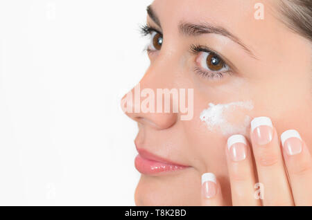 Nahaufnahme Porträt einer jungen Frau mit perfekter Haut anwenden beauty Creme und Blick in den Spiegel Stockfoto