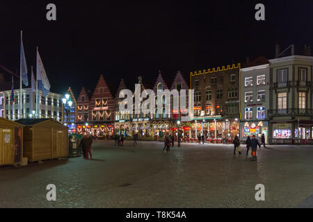 Menschen auf dem großen Marktplatz (Markt) im Zentrum von Brügge, Nacht. Mittelalterliche Häuser sind mit Weihnachtsbeleuchtung, wintermärchen eingerichtet Stockfoto
