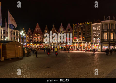 Menschen auf dem großen Marktplatz (Markt) im Zentrum von Brügge, Nacht. Mittelalterliche Häuser sind mit Weihnachtsbeleuchtung, wintermärchen eingerichtet Stockfoto