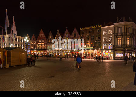 Menschen auf dem großen Marktplatz (Markt) im Zentrum von Brügge, Nacht. Mittelalterliche Häuser sind mit Weihnachtsbeleuchtung, wintermärchen eingerichtet Stockfoto