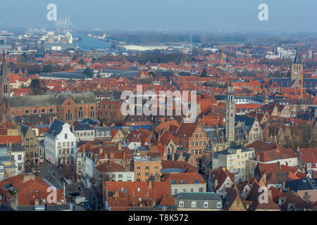 Fantastische Brügge City Skyline mit roten Ziegeldächern, die Poortersloge (burgher's Lodge) Turm und Windmühlen im Hintergrund. Blick auf mittelalterliche Brügge. Stockfoto