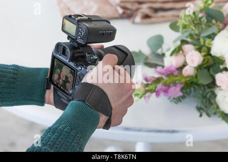 Ein junger Mann macht ein Foto von einer Hochzeit Bouquet, ein Bild auf dem Kameradisplay. Stockfoto
