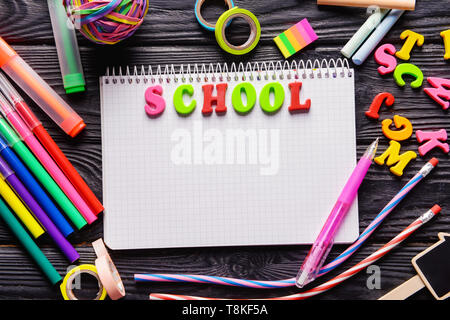 Wort Schule mit Farbe Buchstaben und Schreibwaren auf hölzernen Hintergrund Stockfoto