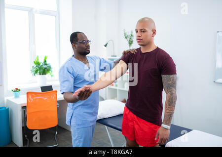 Junge Bodybuilder tragen smart Watch, Physiotherapeuten Stockfoto