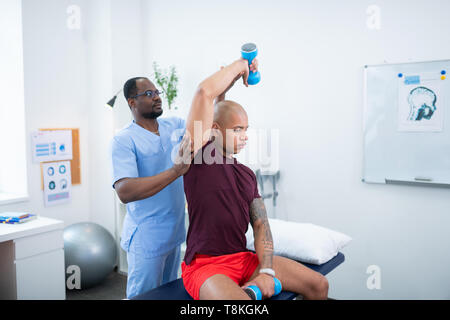 Mann sitzt und Training mit Langhanteln besuchen Therapeuten Stockfoto