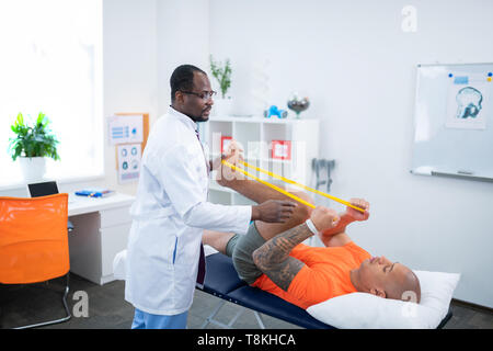 Sportler Übungen für die Beine beim Besuchen der Therapeut Stockfoto