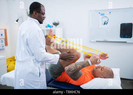 Sportler mit Tattoo auf dem Arm Übungen für die Beine Stockfoto