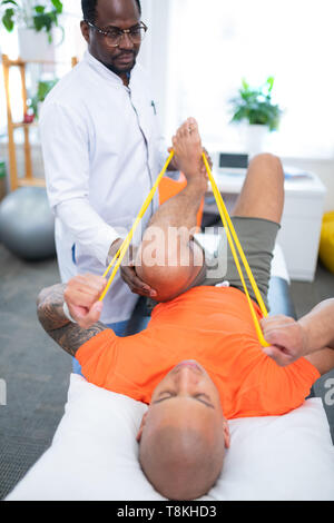 Sportsman in orange T-Shirt tun Rehabilitation Übungen für Beine Stockfoto