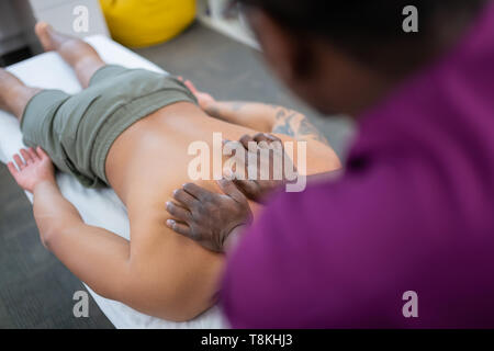 Dunkelhäutige therapeut Rücken- für Mann in Shorts Stockfoto