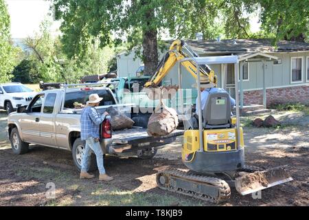 Verschieben von Felsen und der Installation von Rohrleitungen für die Landschaftsgestaltung, die von den mexikanischen Arbeiter mit Bagger und Handwerkzeuge für das Laden und Löschen von Partien in Lake County CA Stockfoto