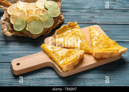 Vorstand mit Stücken von leckeren Zitronenkuchen auf hölzernen Tisch Stockfoto