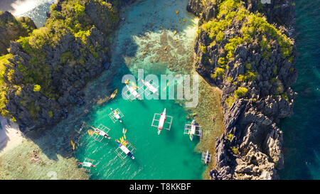 Antenne drone Ansicht von Kajaks in einem schönen flachen tropischen Lagune durch schroffe Felsen und Jungle kleine Lagune umgeben, El Nido Stockfoto