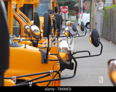 Schulbusse aufgereiht mit konvexen Spiegel auf einem Parkplatz. Stockfoto
