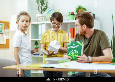 Strahlende dunkelhaarige Student in gelben T-Shirt, kleines Haus Stockfoto