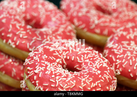 Donuts in rosa Glasur mit Nahaufnahme Streuseln. Bunte süße Krapfen für Hintergrund Stockfoto